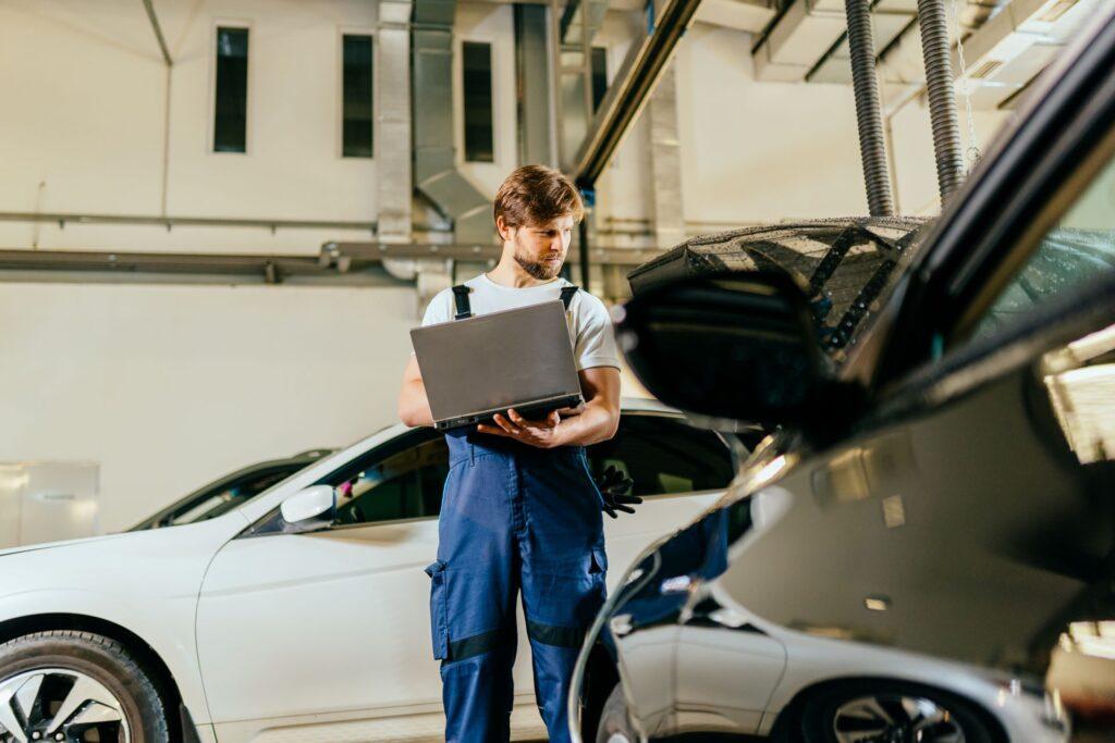 Ein Mechaniker führt mit einem Laptop eine digitale Fahrzeugdiagnose durch, um ein Fahrzeug für die Hauptuntersuchung (HU) in Hanau vorzubereiten.