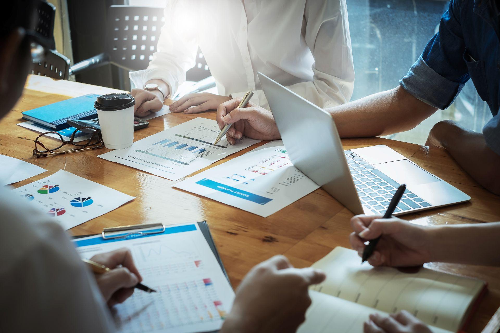 Team arbeitet gemeinsam an Finanzunterlagen und Laptop, Symbol fuer Zusammenarbeit und individuelle Steuerberatung in Neu-Ulm